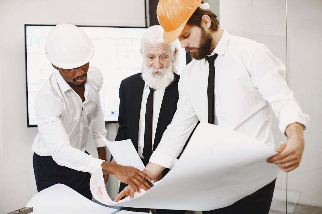 Three architects in office reviewing blueprints, showcasing teamwork and professional attire.